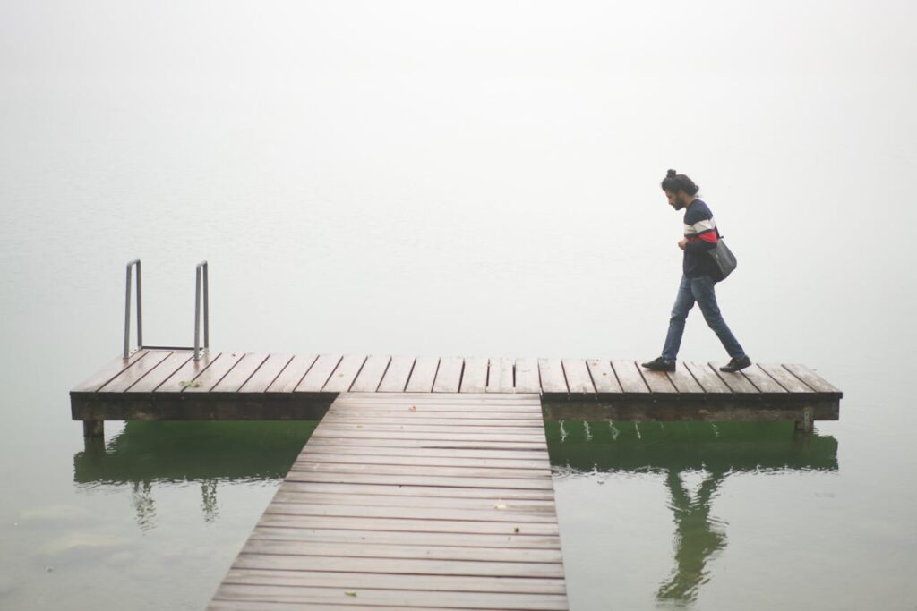 A person walks alone on a misty wooden dock over calm waters in Wels, Austria.