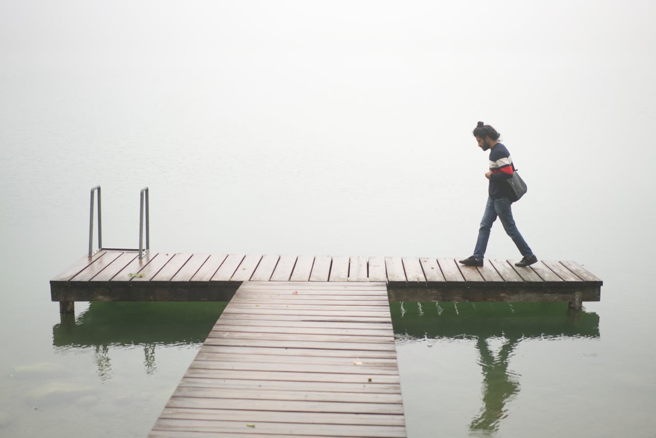 A person walks alone on a misty wooden dock over calm waters in Wels, Austria.